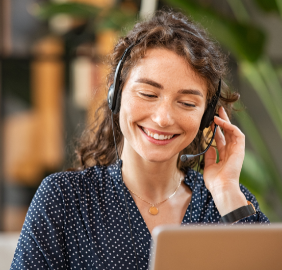 a person smiling with a headset on in front of a computer